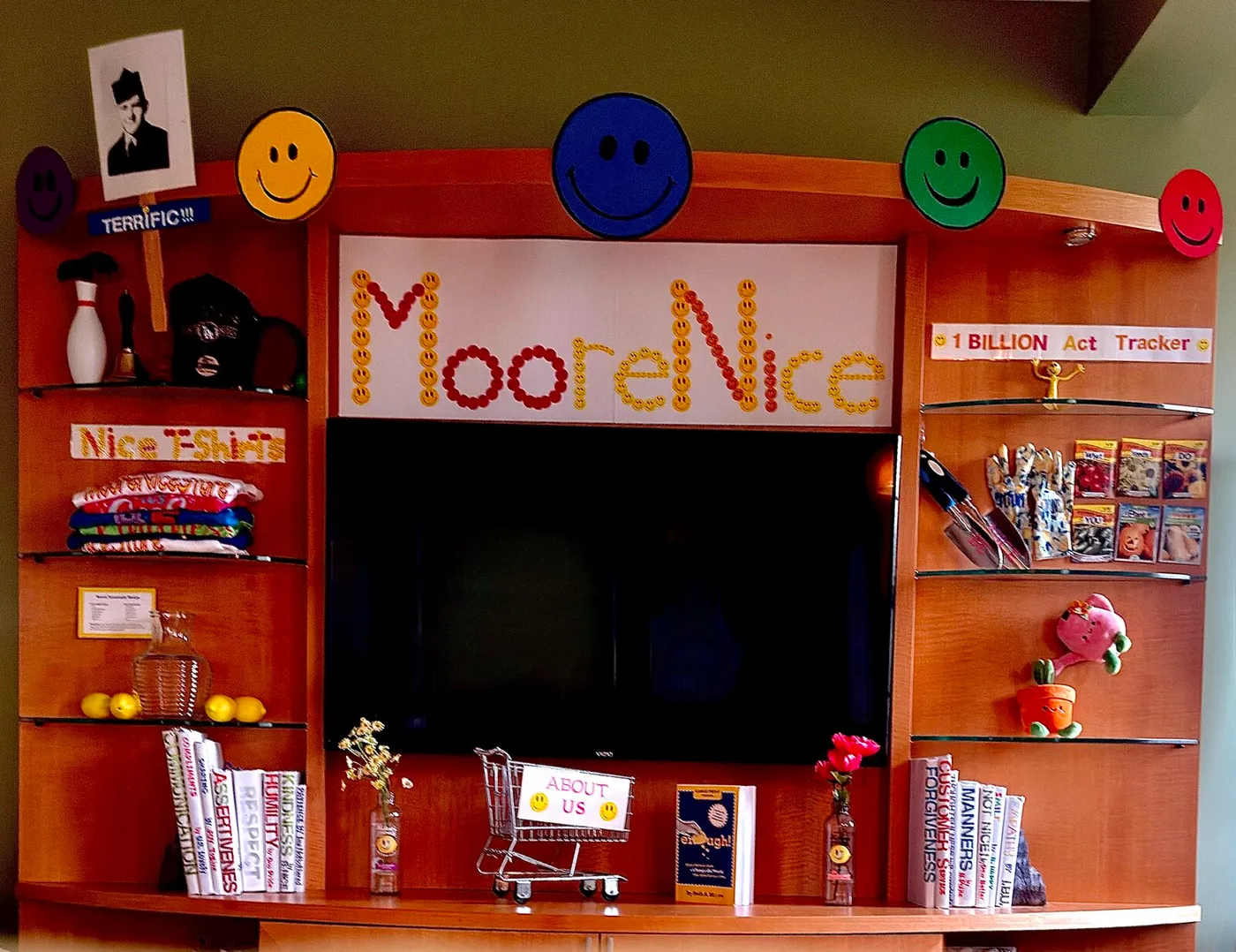 Beth's MooreNice Store — a bookshelf storefront with the 1 BILLION Act Tracker sign, Nice T-Shirts, the lemonade recipe, seed packets, bookend books, and her dad's photo